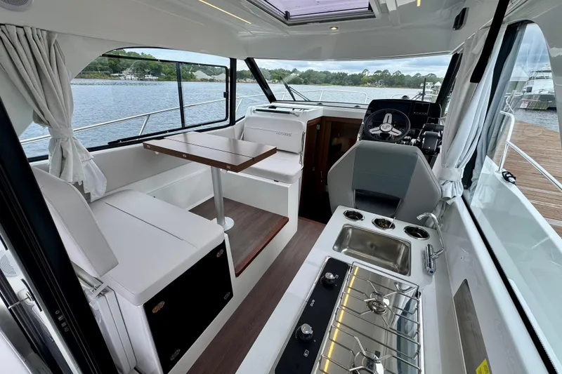 Slide: The Image of Interior of 2026 Beneteau Antares 9, featuring seating, table, and kitchenette with water view. - 12