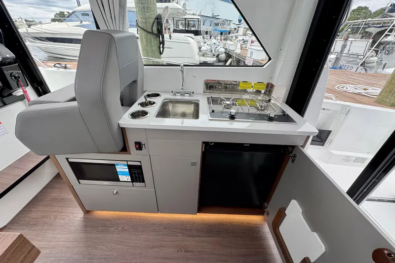 Slide: The Image of Interior of 2026 Beneteau Antares 9, featuring a compact kitchen with stove and sink. - 13