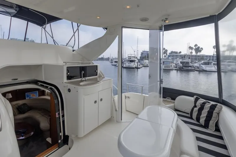 Slide: The Image of 2005 Meridian 459 Motoryacht interior with marina view, featuring seating and kitchenette. - 32