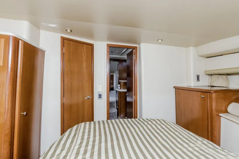 Slide: The Image of Interior of 2005 Meridian 459 Motoryacht bedroom with striped bedding and wooden cabinetry. - 40