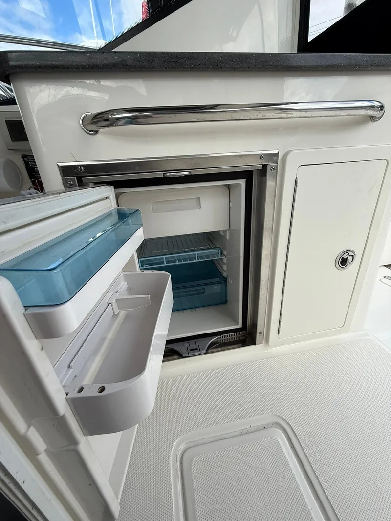 Slide: The Image of 2020 Boston Whaler 325 Conquest boat interior with open mini fridge. - 11