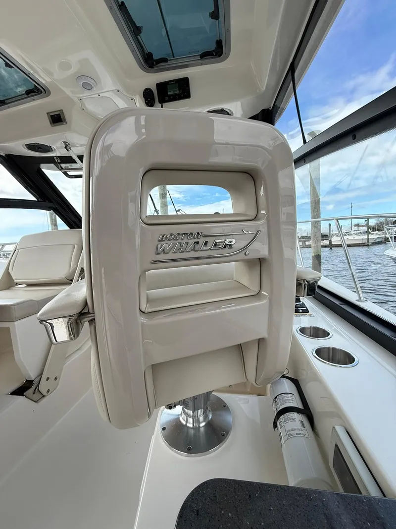 Slide: The Image of 2020 Boston Whaler 325 Conquest interior, featuring a sleek captain's chair and panoramic windows. - 13
