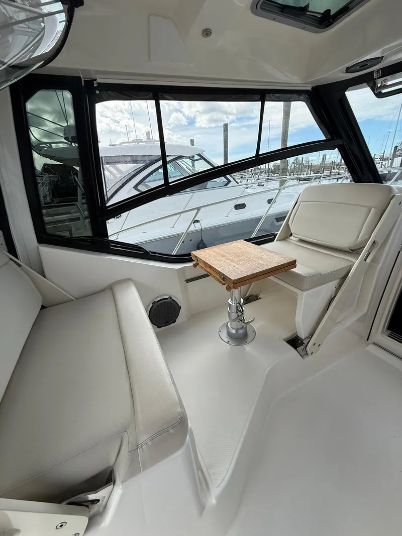Slide: The Image of 2020 Boston Whaler 325 Conquest interior with seating and table, docked at marina. - 16