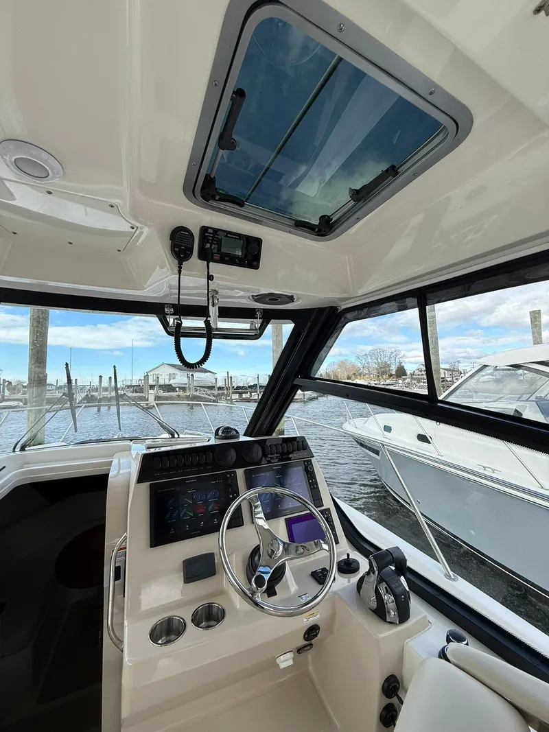 Slide: The Image of 2020 Boston Whaler 325 Conquest helm with modern controls and waterfront view. - 18