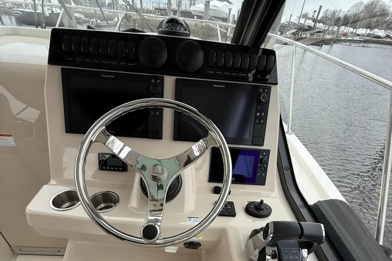 Slide: The Image of 2020 Boston Whaler 325 Conquest helm with dual displays and steering wheel. - 2