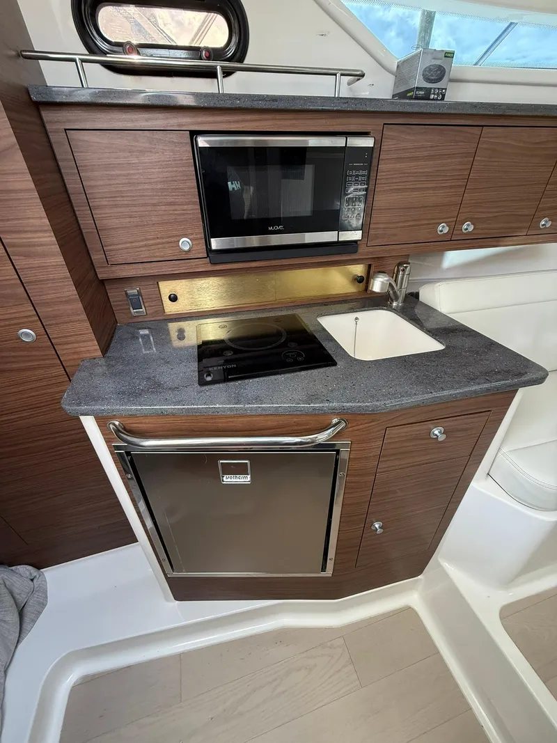 Slide: The Image of 2020 Boston Whaler 325 Conquest galley with microwave, sink, and compact fridge. - 20