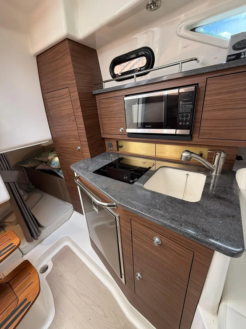 Slide: The Image of 2020 Boston Whaler 325 Conquest interior kitchen with modern appliances and wood cabinetry. - 27