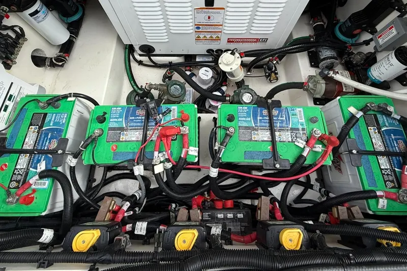 Slide: The Image of 2020 Boston Whaler 325 Conquest boat battery compartment with multiple green batteries and wiring. - 37
