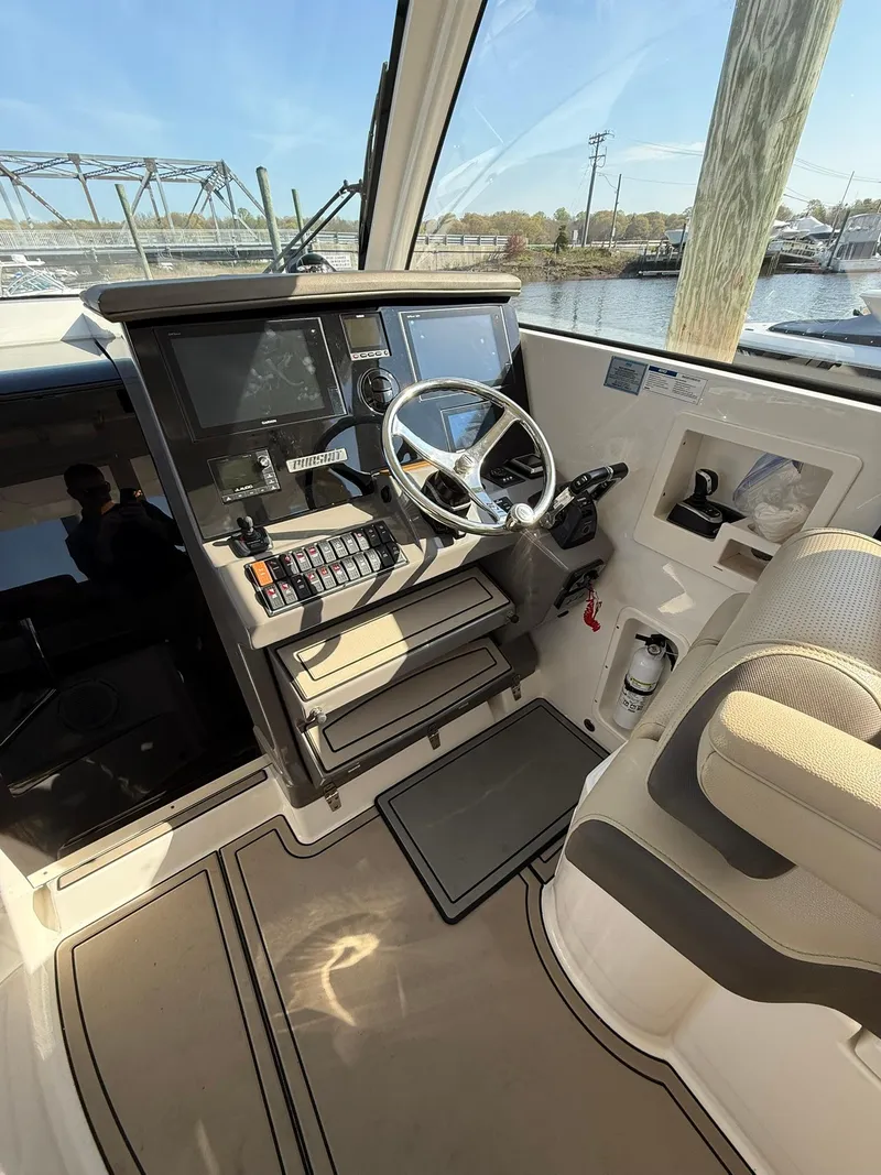 Slide: The Image of 2020 Boston Whaler 325 Conquest helm with modern controls and waterfront view. - 49