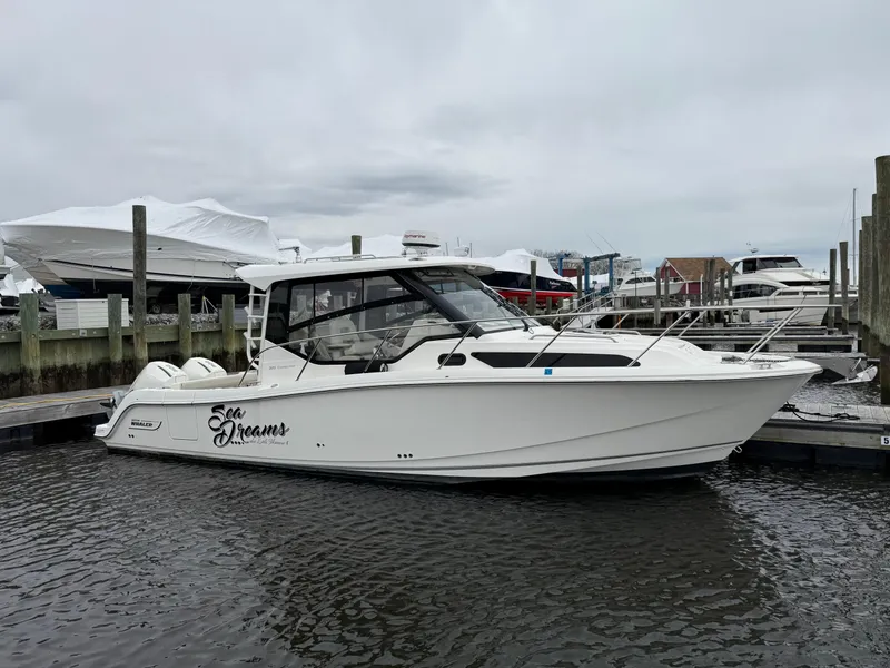 Slide: The Image of 2020 Boston Whaler 325 Conquest boat docked in a marina under cloudy skies. - 5