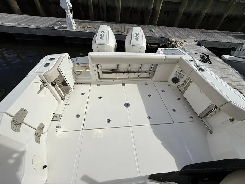Slide: The Image of 2020 Boston Whaler 325 Conquest boat deck with dual engines and fishing rod holders. - 8