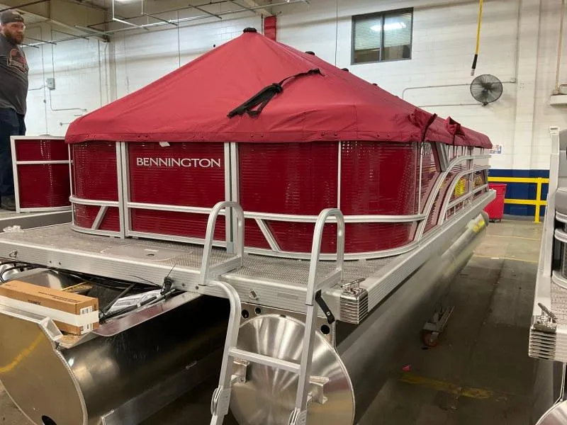 Slide: The Image of 2024 Bennington 20 SVSR SPS pontoon boat with red cover in a warehouse. - 3