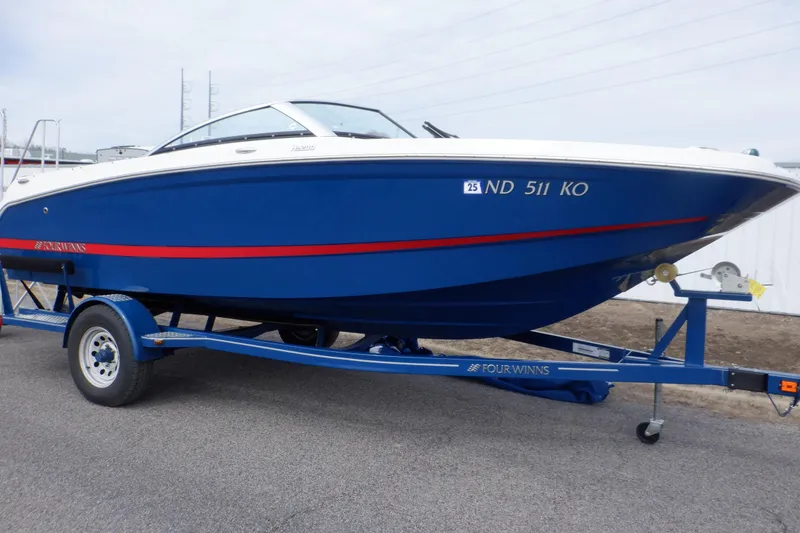 Slide: The Image of 2018 Four Winns HD200 boat on trailer, blue with red stripe, parked outdoors. - 1