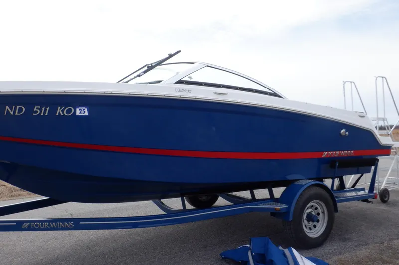 Slide: The Image of 2018 Four Winns HD200 boat on trailer, blue with red stripe, parked outdoors. - 13