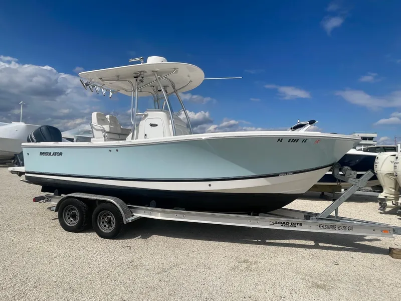 Slide: The Image of 2017 Regulator 23 FS Center Console boat on trailer, parked outdoors under blue sky. - 0