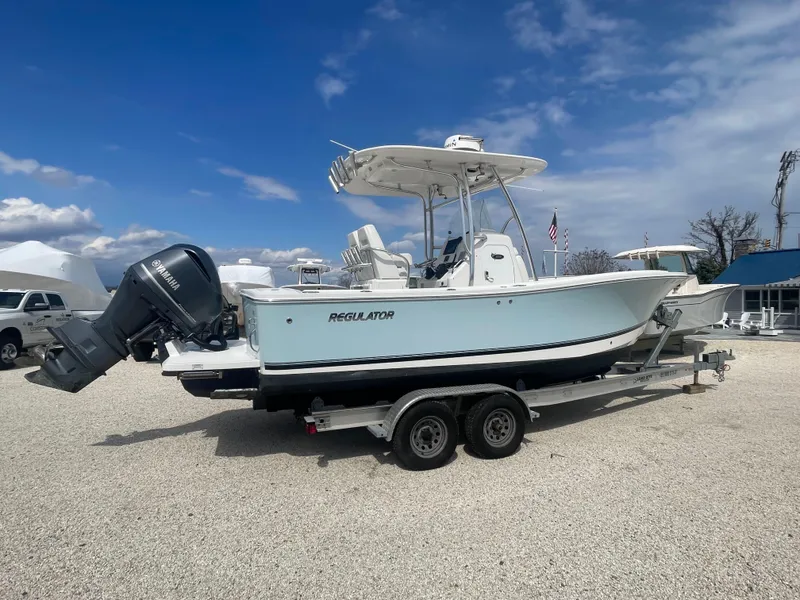 Slide: The Image of 2017 Regulator 23 FS Center Console boat on trailer, parked outdoors under blue sky. - 2