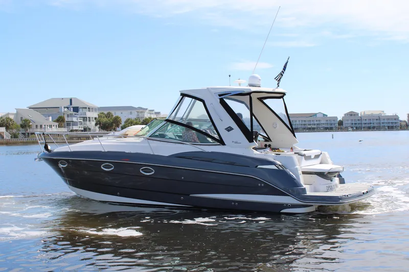 Slide: The Image of 2013 Monterey 340 Sport Yacht cruising on a calm lake near waterfront homes. - 2