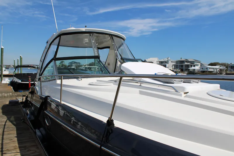 Slide: The Image of 2013 Monterey 340 Sport Yacht docked, showcasing sleek design and spacious deck under clear skies. - 20