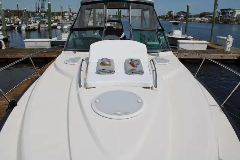 Slide: The Image of 2013 Monterey 340 Sport Yacht docked, featuring sunbathing area with towels and scenic marina backdrop. - 32