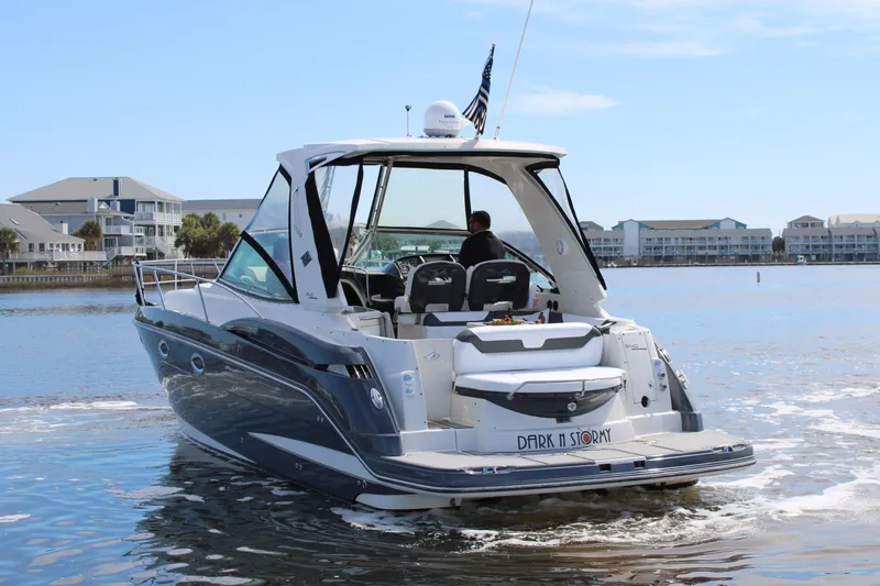 Slide: The Image of 2013 Monterey 340 Sport Yacht cruising on a calm waterway, with buildings in the background. - 4