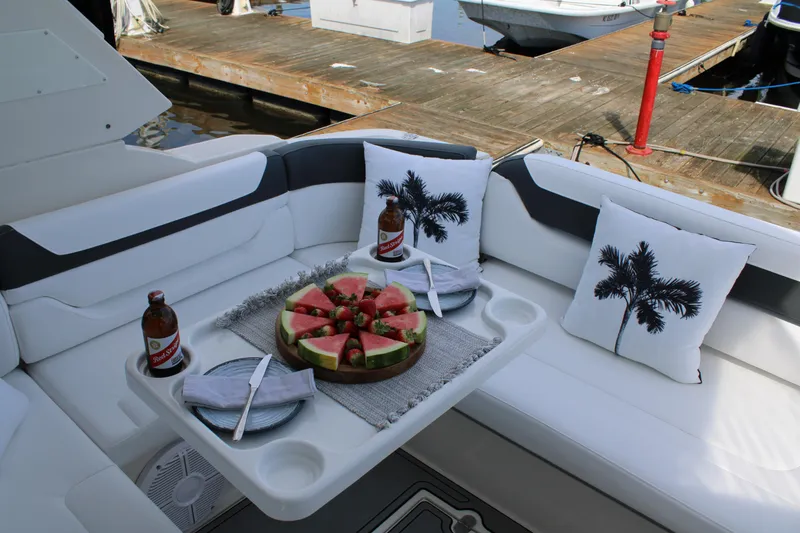 Slide: The Image of 2013 Monterey 340 Sport Yacht interior with watermelon, drinks, and palm-themed pillows on a docked boat. - 55