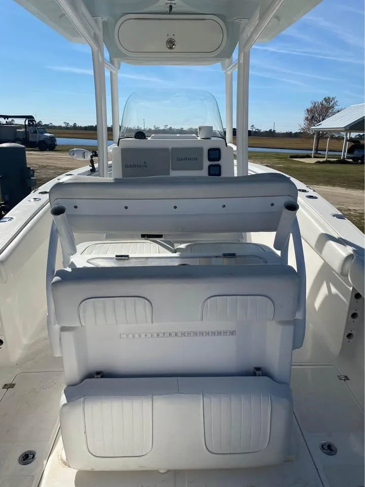 Slide: The Image of 2014 Sea Fox 256 Commander boat interior with seating and console, docked outdoors. - 6