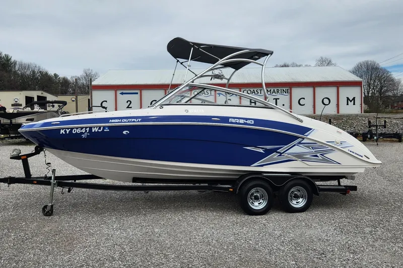 Slide: The Image of 2011 Yamaha AR240 High Output boat on trailer, blue and white design, parked outdoors. - 1