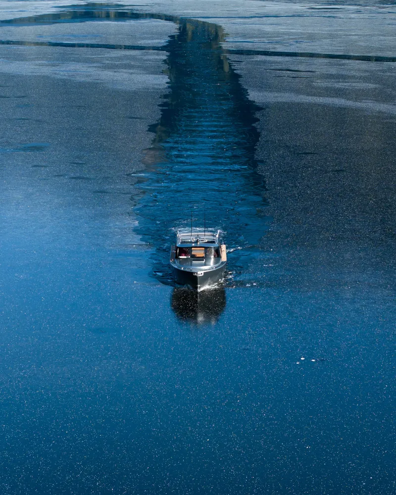 Slide: The Image of 2025 Jasper Marine Defender 22 boat cruising on calm, reflective water. - 2