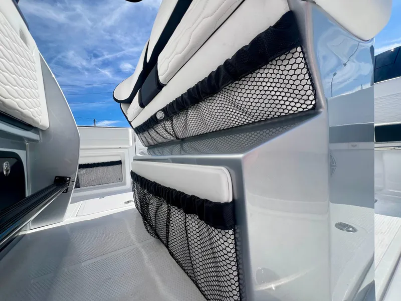 Slide: The Image of 2025 Nor-Tech 390 Sport Center Console interior with white seating and netted storage. - 26