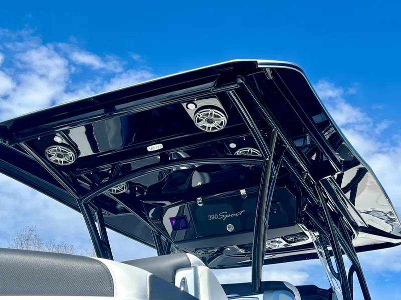 Slide: The Image of 2025 Nor-Tech 390 Sport Center Console boat with sleek black canopy against blue sky. - 46