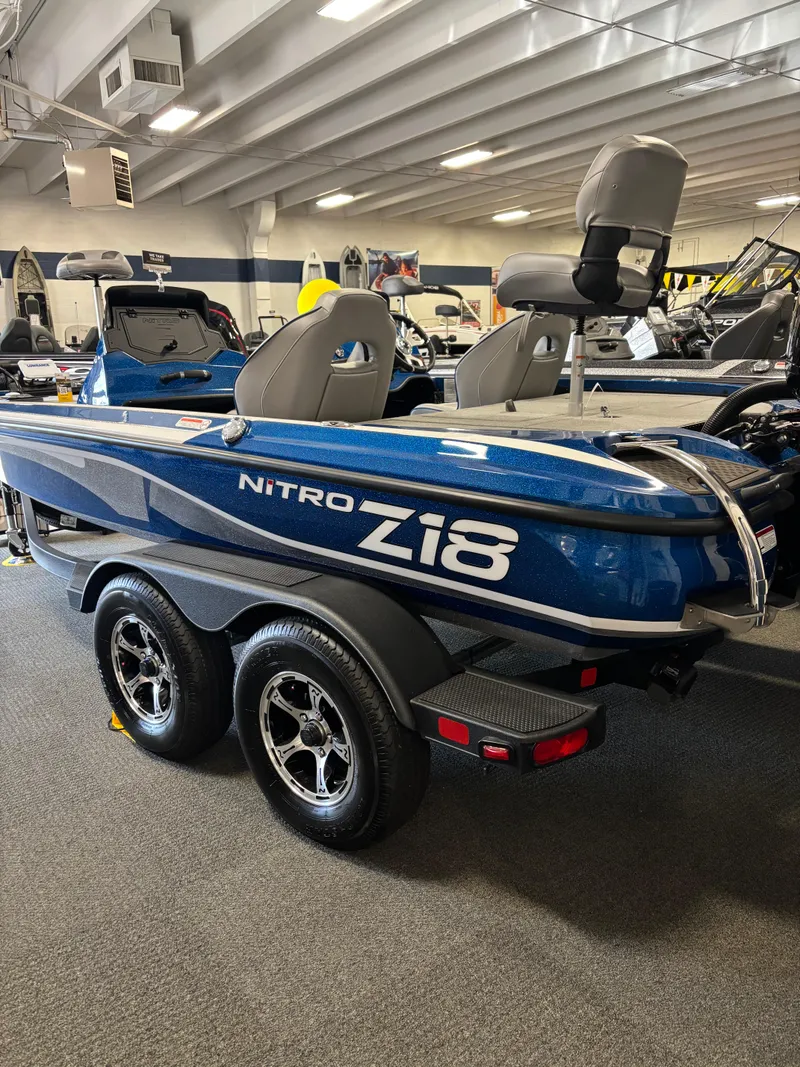 Slide: The Image of 2024 Nitro Z18Pro boat in showroom, blue exterior, dual seats, trailer attached. - 1
