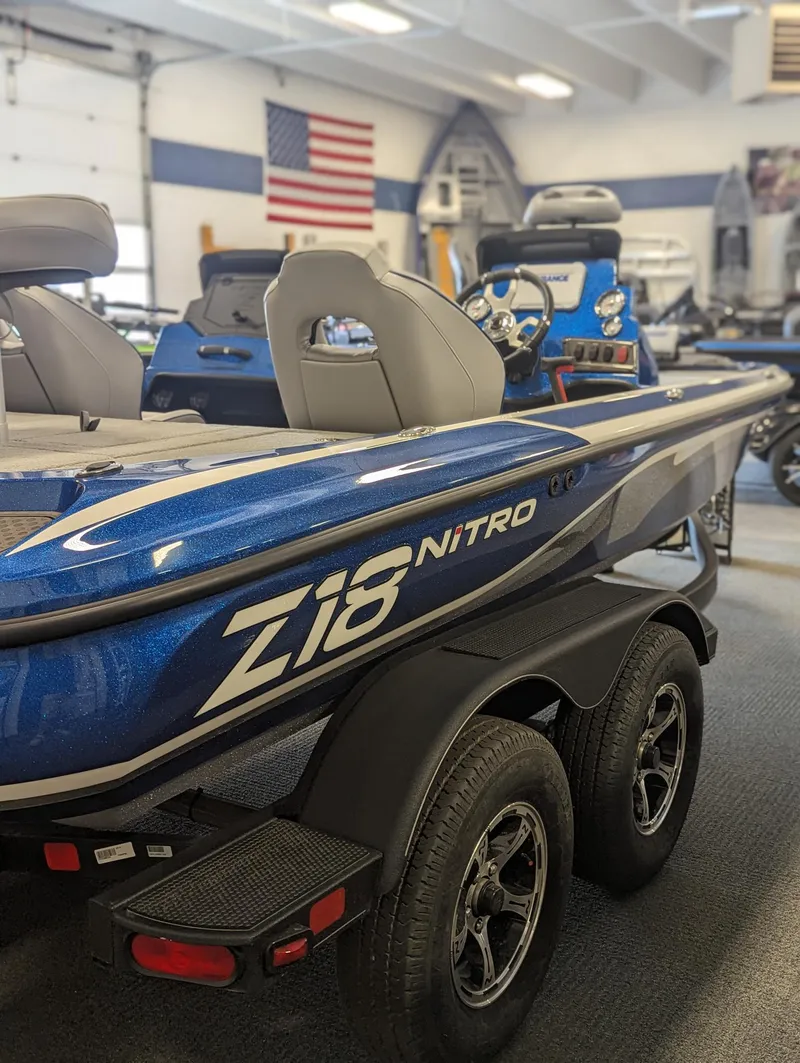 Slide: The Image of 2024 Nitro Z18Pro boat in showroom, blue exterior, dual axle trailer, American flag in background. - 10