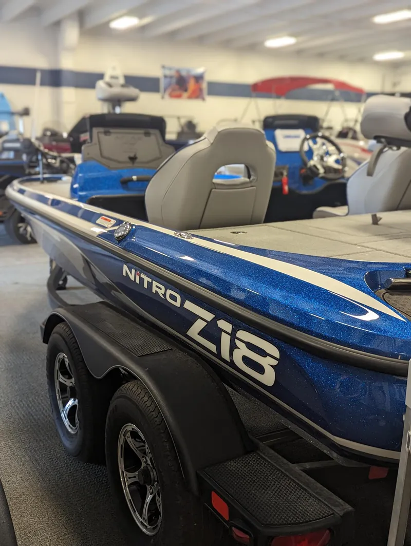 Slide: The Image of 2024 Nitro Z18Pro boat in showroom, featuring sleek blue design and dual-axle trailer. - 11