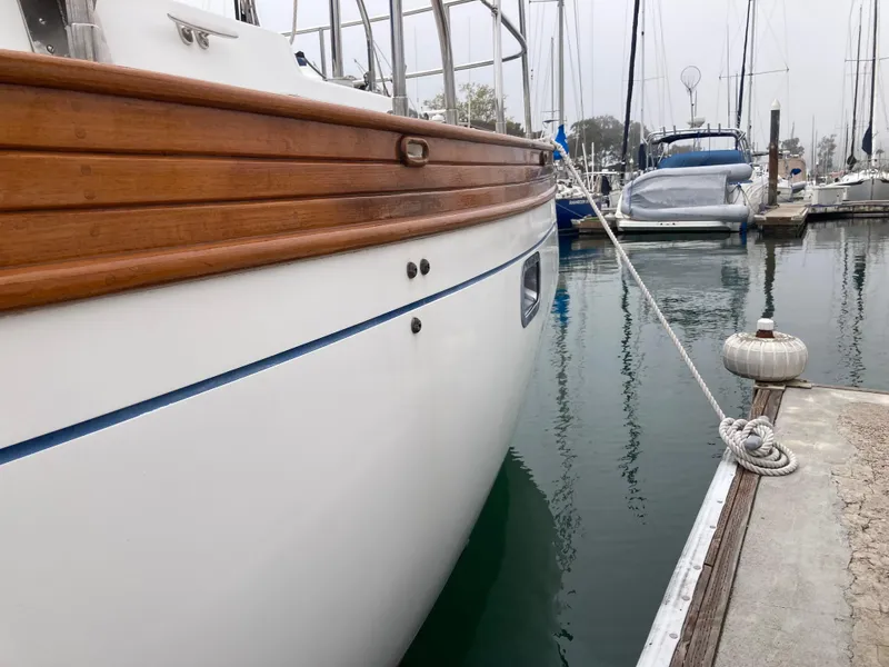 Slide: The Image of 1984 Nantucket Island 33 yacht docked in marina, featuring wooden trim and sleek white hull. - 12