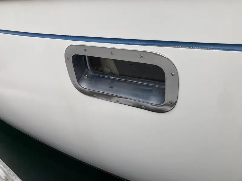 Slide: The Image of Porthole on 1984 Nantucket Island 33 boat, featuring sleek white and blue design. - 13