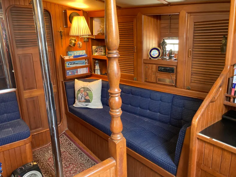 Slide: The Image of Cozy 1984 Nantucket Island 33 yacht interior with wooden paneling and blue cushioned seating. - 40
