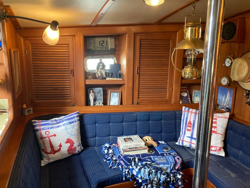 Slide: The Image of Cozy nautical-themed cabin interior with blue seating, decorative pillows, and wooden accents on a 1984 Nantucket Island 33. - 44