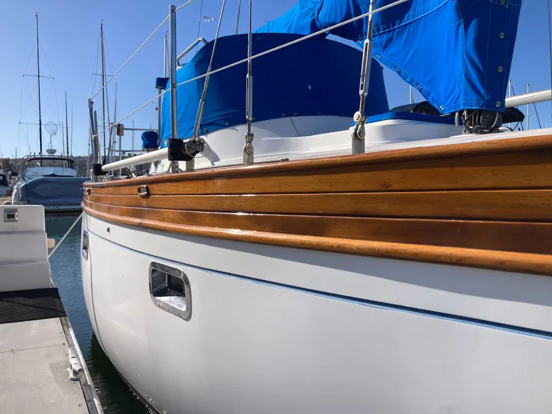 Slide: The Image of 1984 Nantucket Island 33 sailboat with wooden trim and blue cover docked at marina. - 9