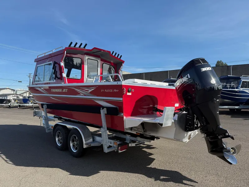 Slide: The Image of 2025 Thunder Jet 24 Alexis Pro boat on trailer, red exterior, powerful outboard motor. - 2