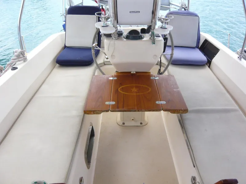 Slide: The Image of Cockpit of 2008 Island Packet 465 sailboat with wooden table and cushioned seating. - 18