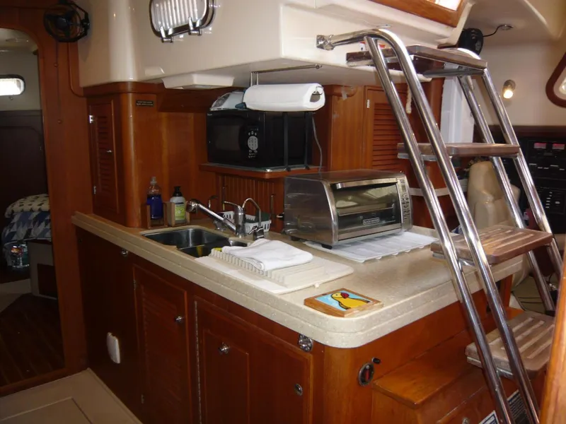 Slide: The Image of 2008 Island Packet 465 yacht interior kitchen with sink, microwave, and ladder. - 26