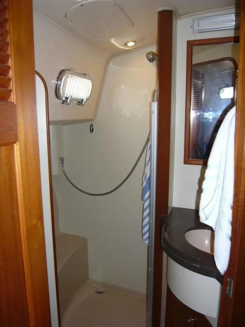 Slide: The Image of 2008 Island Packet 465 yacht bathroom with shower, sink, and wooden accents. - 33