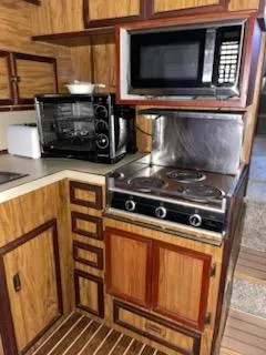 Slide: The Image of 1980 Viking 43 Double Cabin kitchen with stove, microwave, and wooden cabinetry. - 10