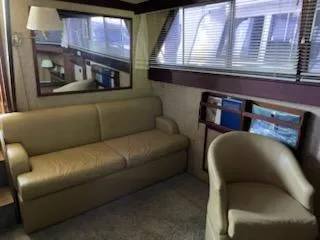 Slide: The Image of 1980 Viking 43 Double Cabin interior with beige sofa, chair, and large window blinds. - 8