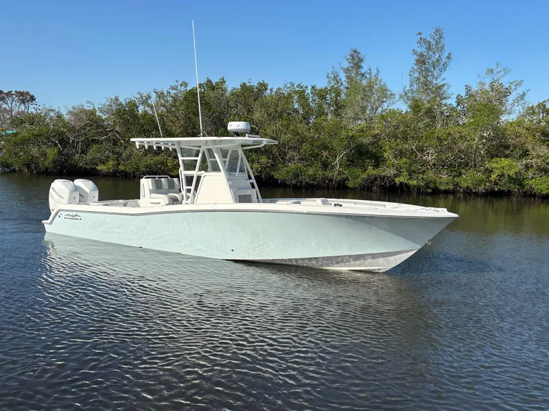 Slide: The Image of 2018 Invincible 33 Open Fisherman boat on calm water, surrounded by lush greenery. - 0
