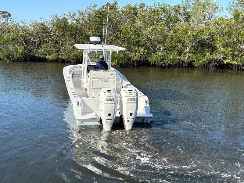 Slide: The Image of 2018 Invincible 33 Open Fisherman boat navigating a calm waterway with twin engines. - 10