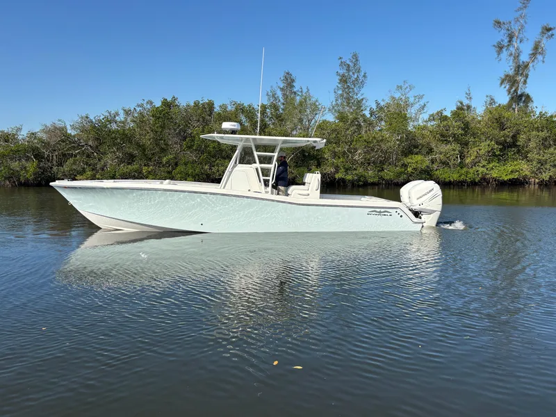Slide: The Image of 2018 Invincible 33 Open Fisherman boat on calm water, surrounded by lush greenery. - 3