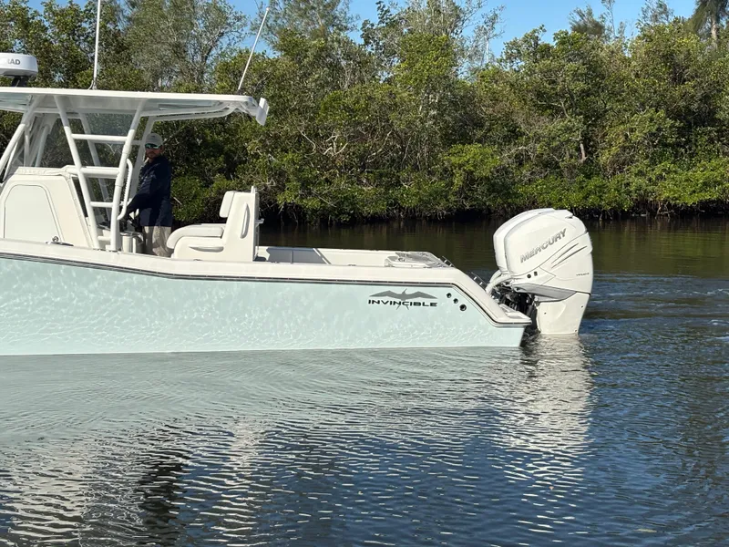 Slide: The Image of 2018 Invincible 33 Open Fisherman boat on calm water near lush greenery. - 8