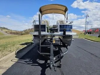 Slide: The Image of 2023 Sun Tracker Bass Buggy 16 XL Select pontoon boat on a trailer, parked outdoors. - 12