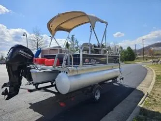 Slide: The Image of 2023 Sun Tracker Bass Buggy 16 XL Select pontoon boat on trailer, parked outdoors. - 3